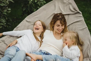 Melegséget sugárzó közeli kép: egy anya gyengéden az ölében tartja kisgyermekét, miközben egymásra mosolyognak, kifejezve a biztonságos kötődést és az érzelmi összhangot.