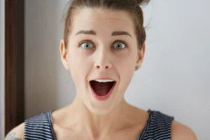 Közeli kép egy fiatal lányról, aki kinyitja a száját, szemléltetve a szájüreg és a nyelv elhelyezkedésének fontosságát az egészséges fejlődésben.