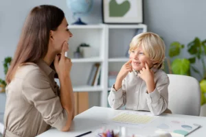 Egy logopédus szakember türelmesen foglalkozik egy kisfiúval, játékos formában segítve a helyes beszédhangok és az artikuláció kialakítását.
