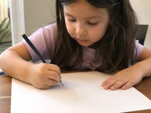 Egy kislány túl halvány vonalakat húz rajzolás közben